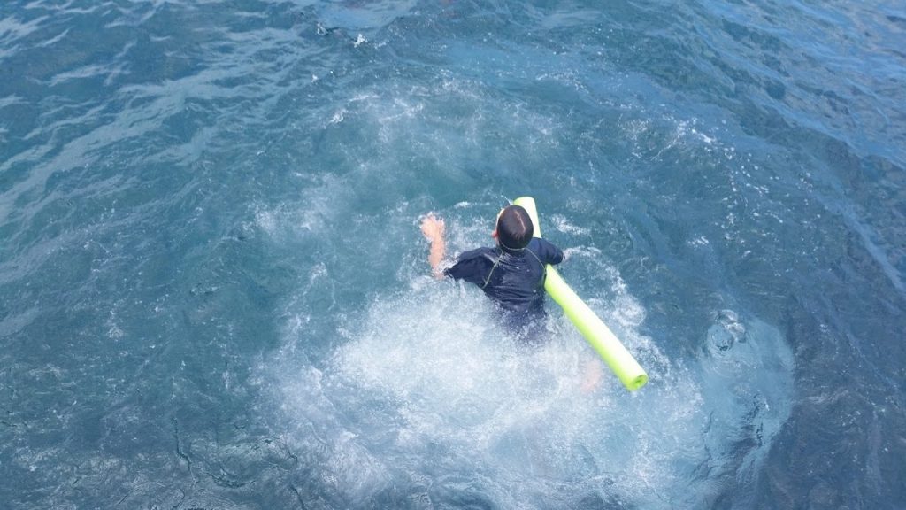 Kid in water with float noodle